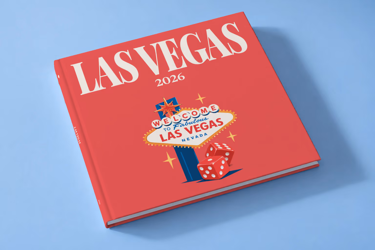 Las Vegas square hardcover photo book with the illustrated cover of the Welcome to Fabulous Las Vegas sign and red dice on red, lying on a pale blue studio backdrop