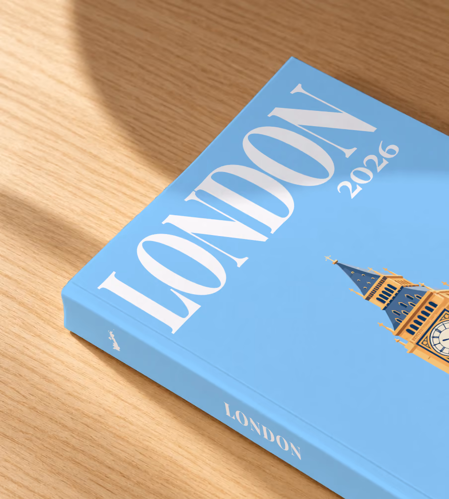 London softcover photo book with the illustrated cover of Big Ben's Elizabeth Tower on sky blue, lying on an oak desk in dappled afternoon sunlight