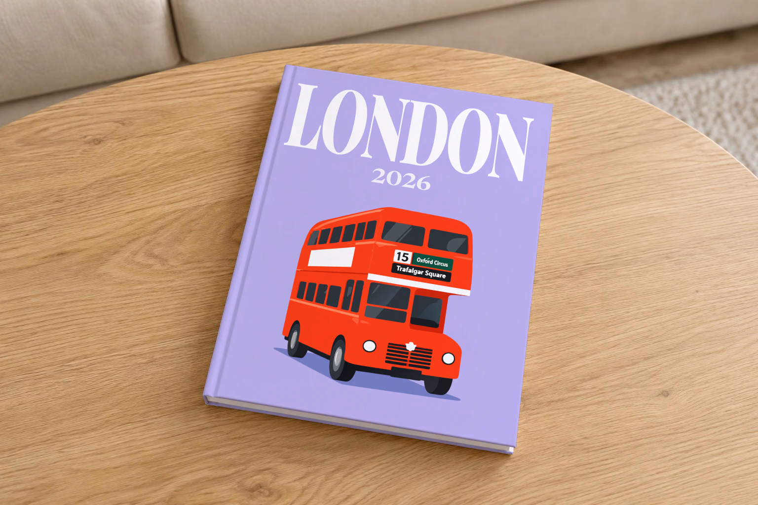 London hardcover photo book with the illustrated cover of a red double-decker London bus to Oxford Circus and Trafalgar Square on lavender, on a round oak coffee table in a bright living room