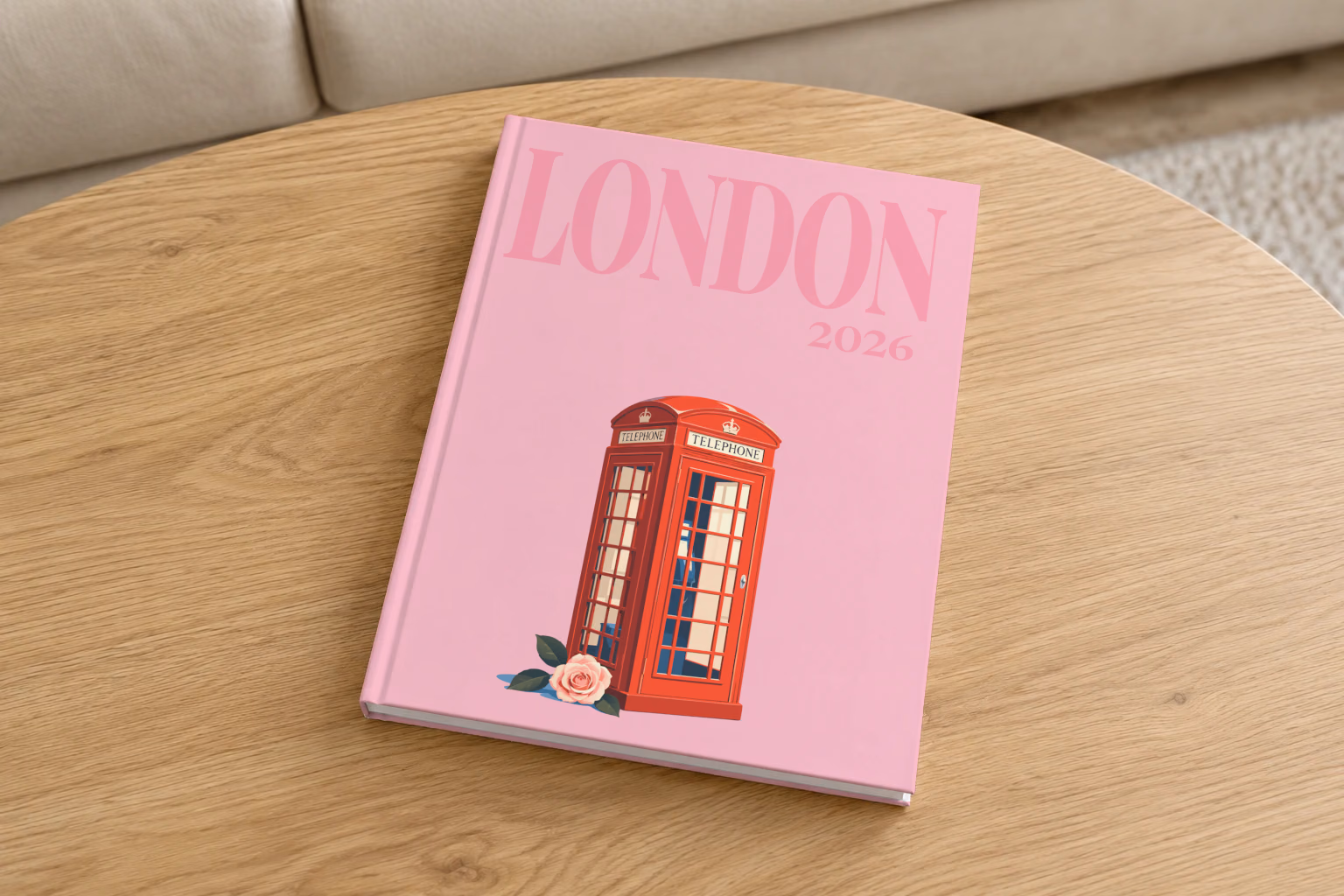 London hardcover photo book with the illustrated cover of a red London telephone box and a pink rose on pink, on a round oak coffee table in a bright living room