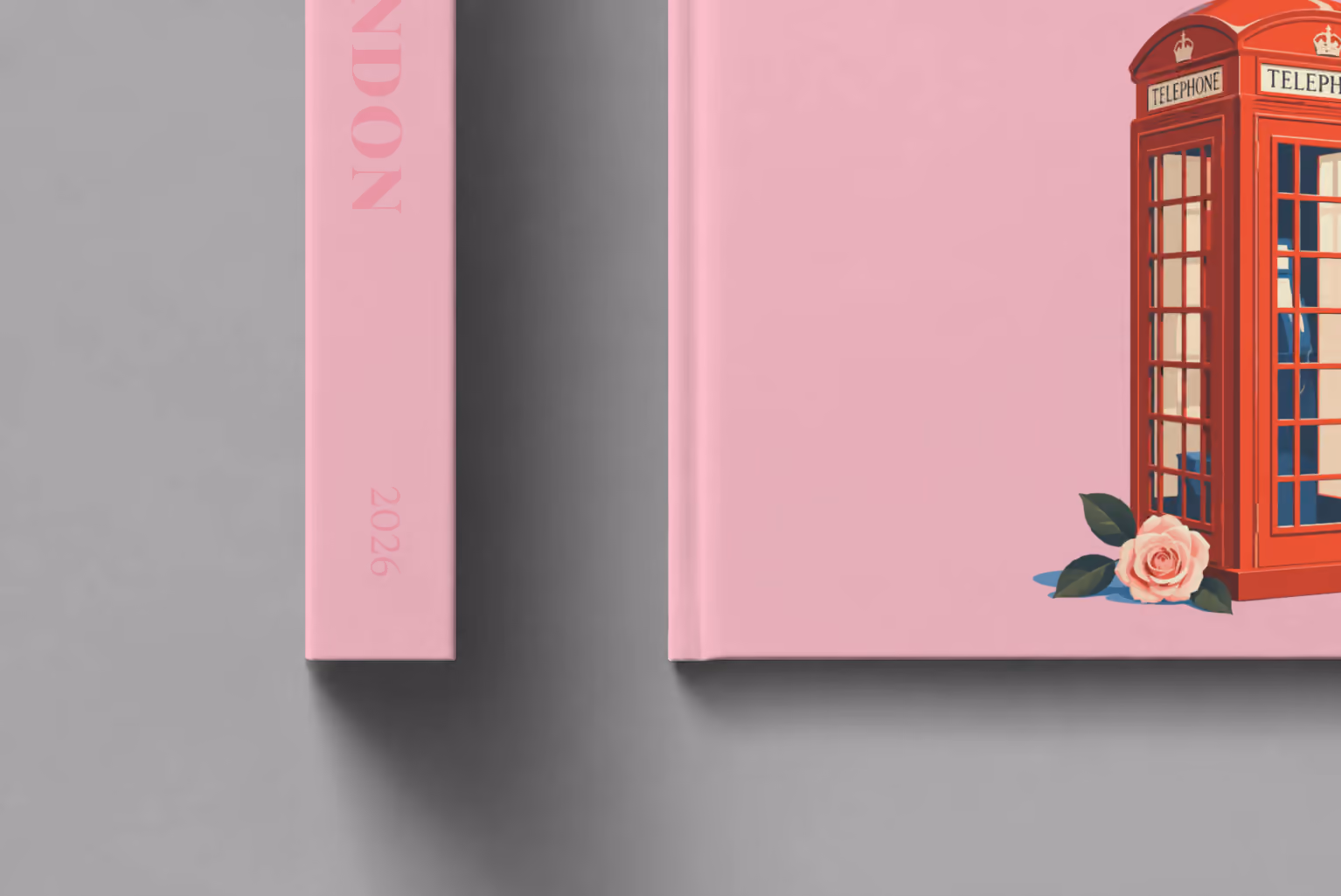 London hardcover photo book with the illustrated cover of a red London telephone box and a pink rose on pink, shown close up beside its spine on a pale grey studio surface