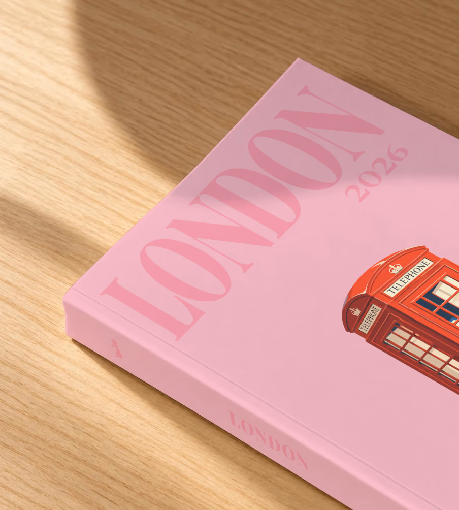 London softcover photo book with the illustrated cover of a red London telephone box and a pink rose on pink, lying on an oak desk in dappled afternoon sunlight