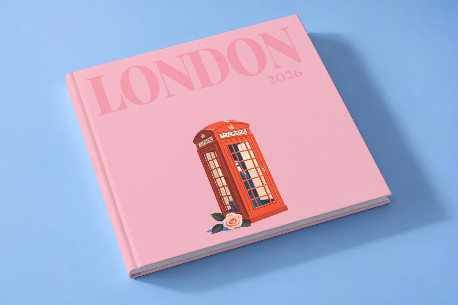 London square hardcover photo book with the illustrated cover of a red London telephone box and a pink rose on pink, lying on a pale blue studio backdrop