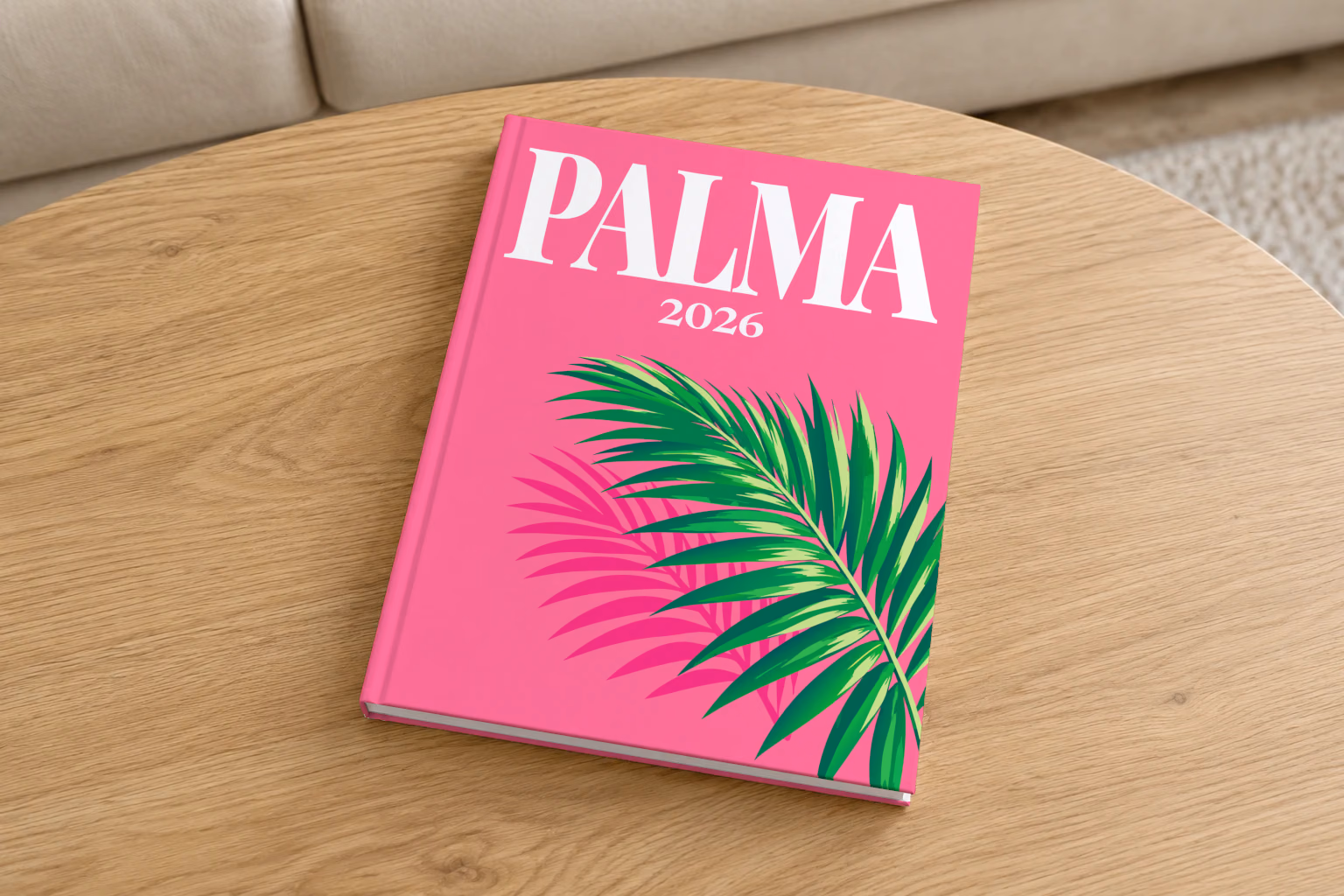 Mallorca hardcover photo book with the Palma illustrated cover of a palm frond on hot pink, on a round oak coffee table in a bright living room