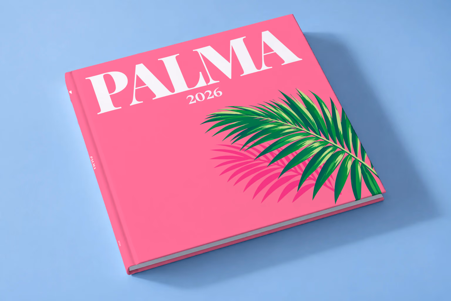 Mallorca square hardcover photo book with the Palma illustrated cover of a palm frond on hot pink, lying on a pale blue studio backdrop