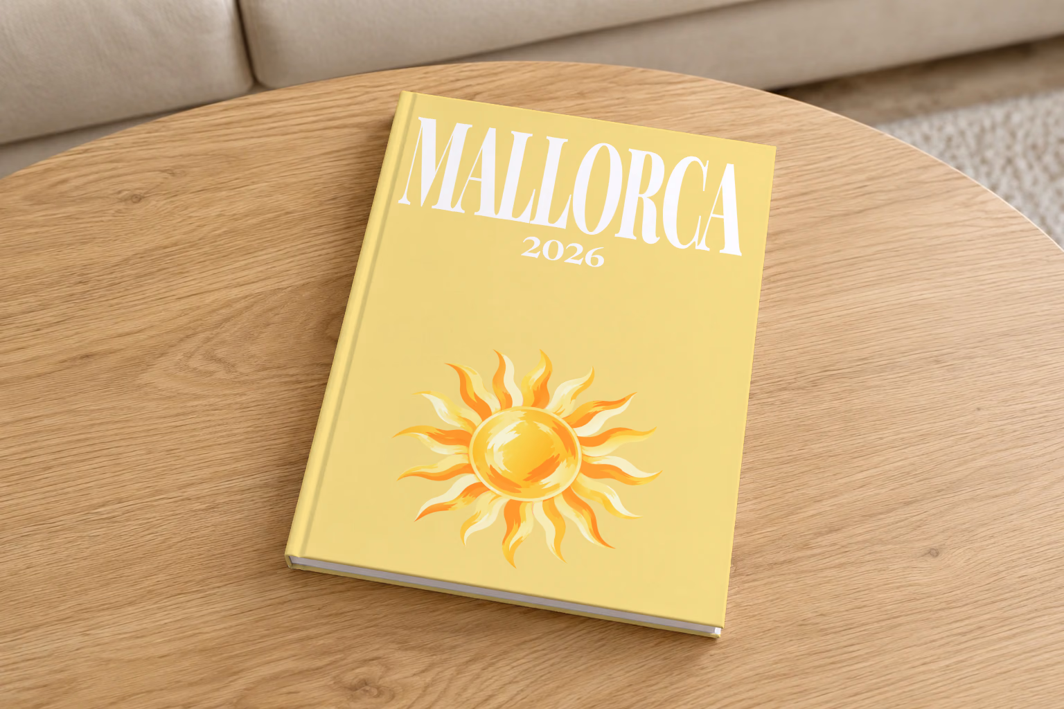 Mallorca hardcover photo book with the illustrated cover of a golden sun on pale yellow, on a round oak coffee table in a bright living room