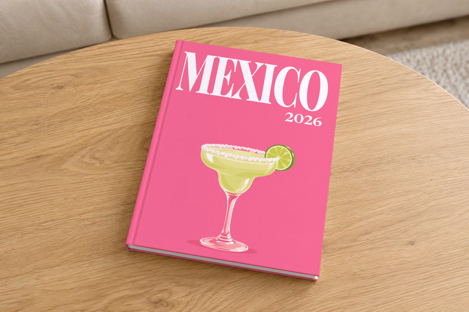 Mexico hardcover photo book with the illustrated cover of a margarita with lime on hot pink, on a round oak coffee table in a bright living room