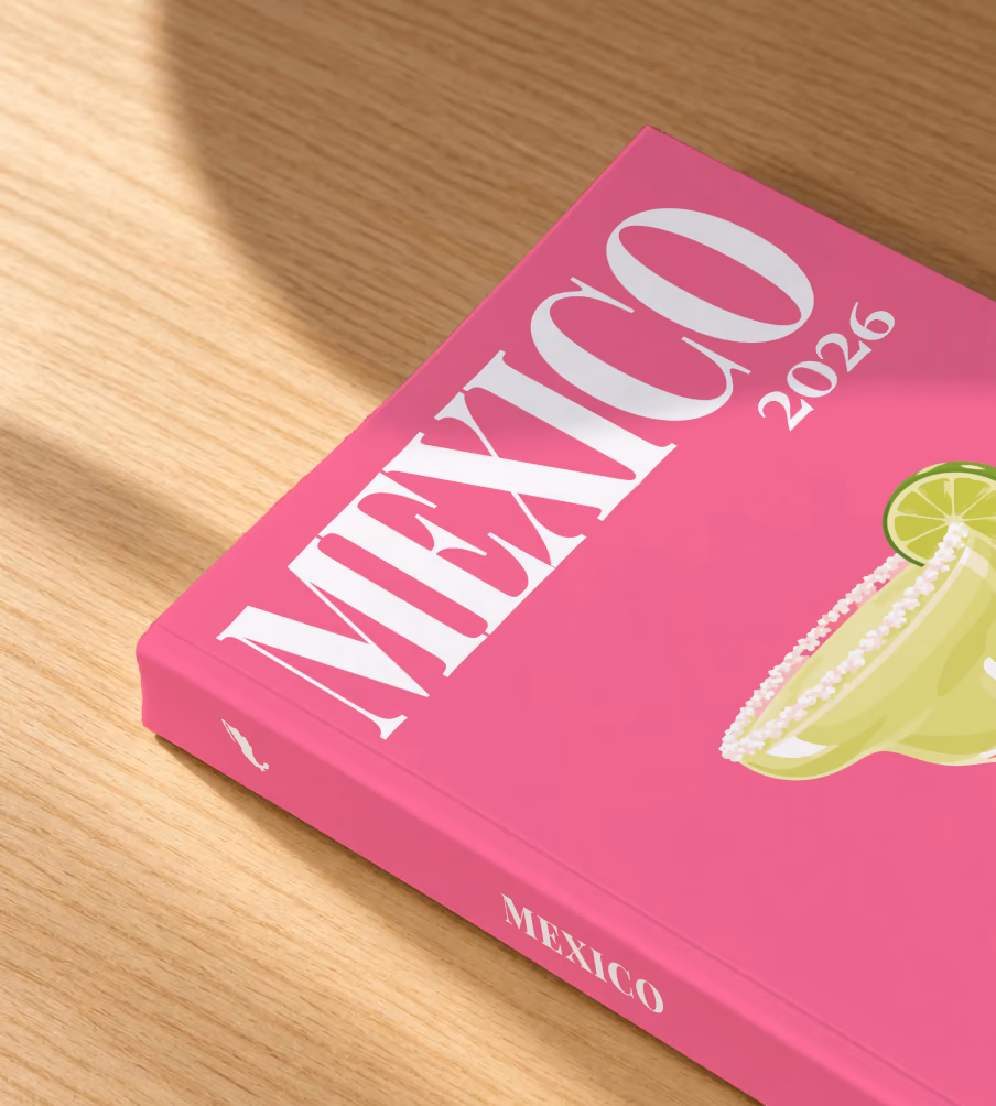 Mexico softcover photo book with the illustrated cover of a margarita with lime on hot pink, lying on an oak desk in dappled afternoon sunlight