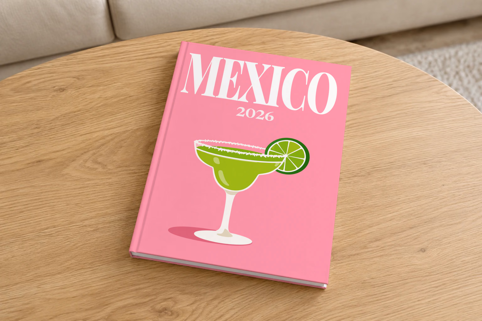 Mexico hardcover photo book with the illustrated cover of a margarita with lime on pink, on a round oak coffee table in a bright living room