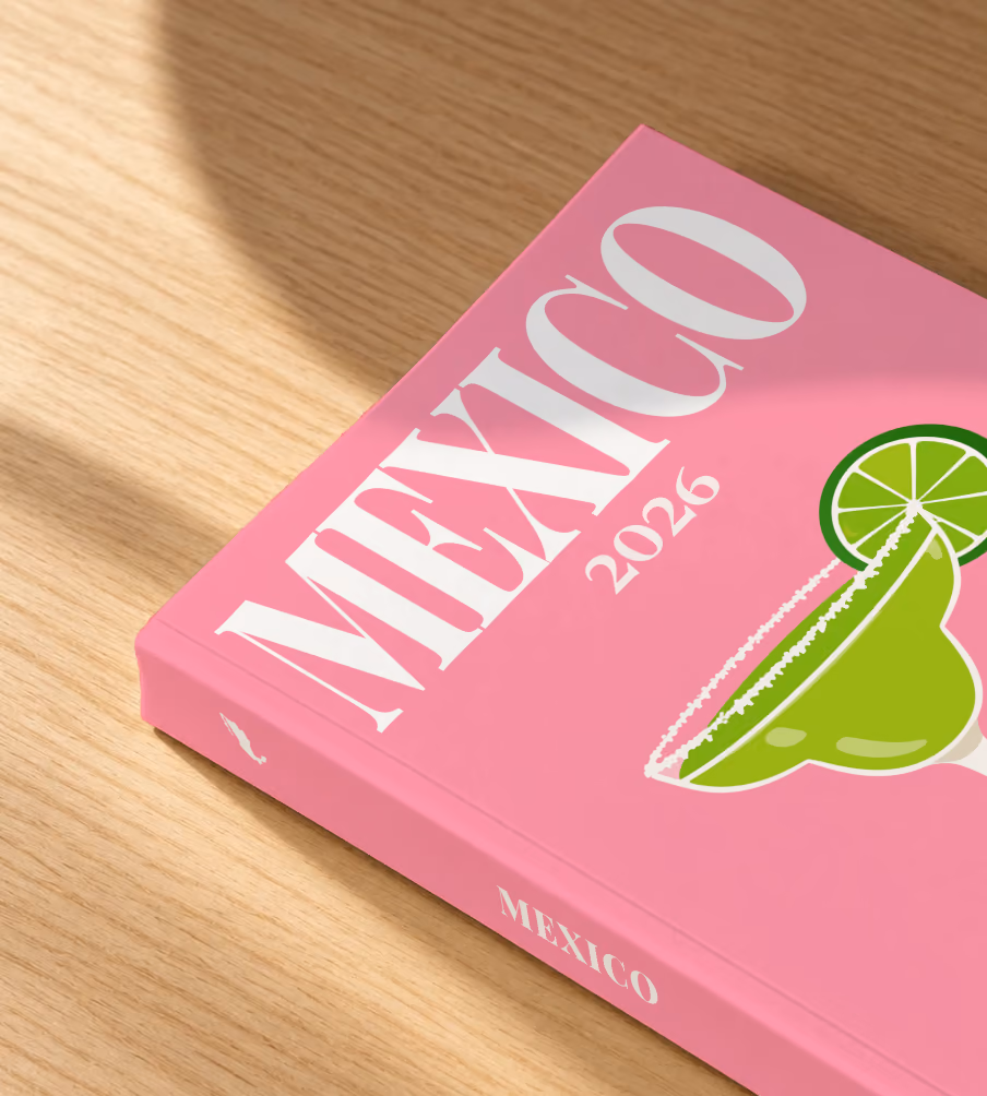 Mexico softcover photo book with the illustrated cover of a margarita with lime on pink, lying on an oak desk in dappled afternoon sunlight