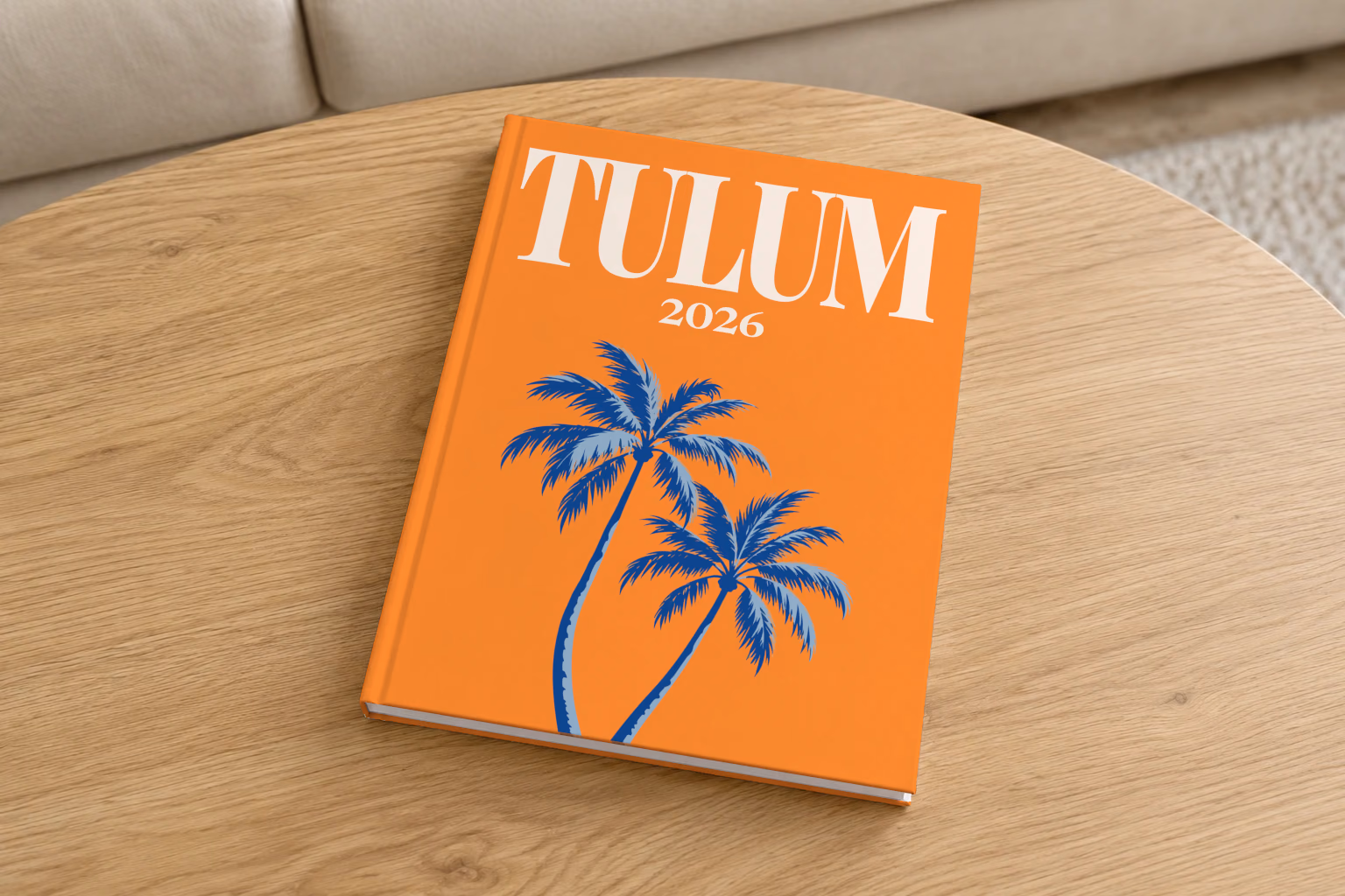 Mexico hardcover photo book with the Tulum illustrated cover of palm trees on orange, on a round oak coffee table in a bright living room