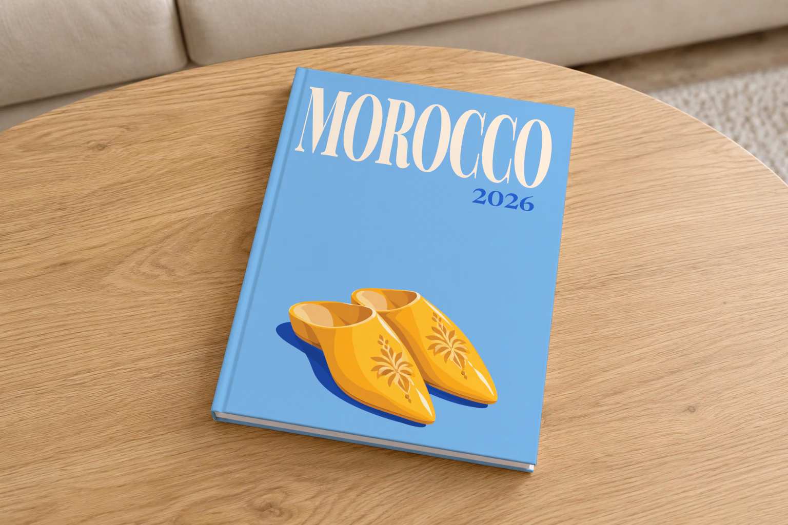 Morocco hardcover photo book with the illustrated cover of a pair of yellow Moroccan babouche slippers on sky blue, on a round oak coffee table in a bright living room