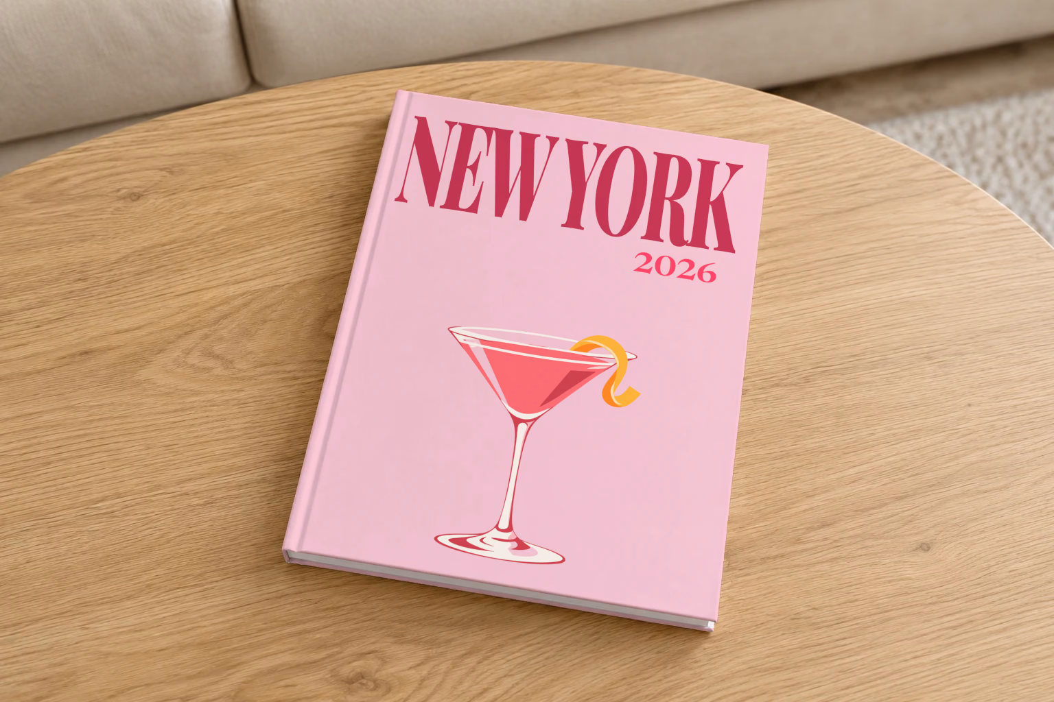 New York hardcover photo book with the illustrated cover of a cosmopolitan on pale pink, on a round oak coffee table in a bright living room