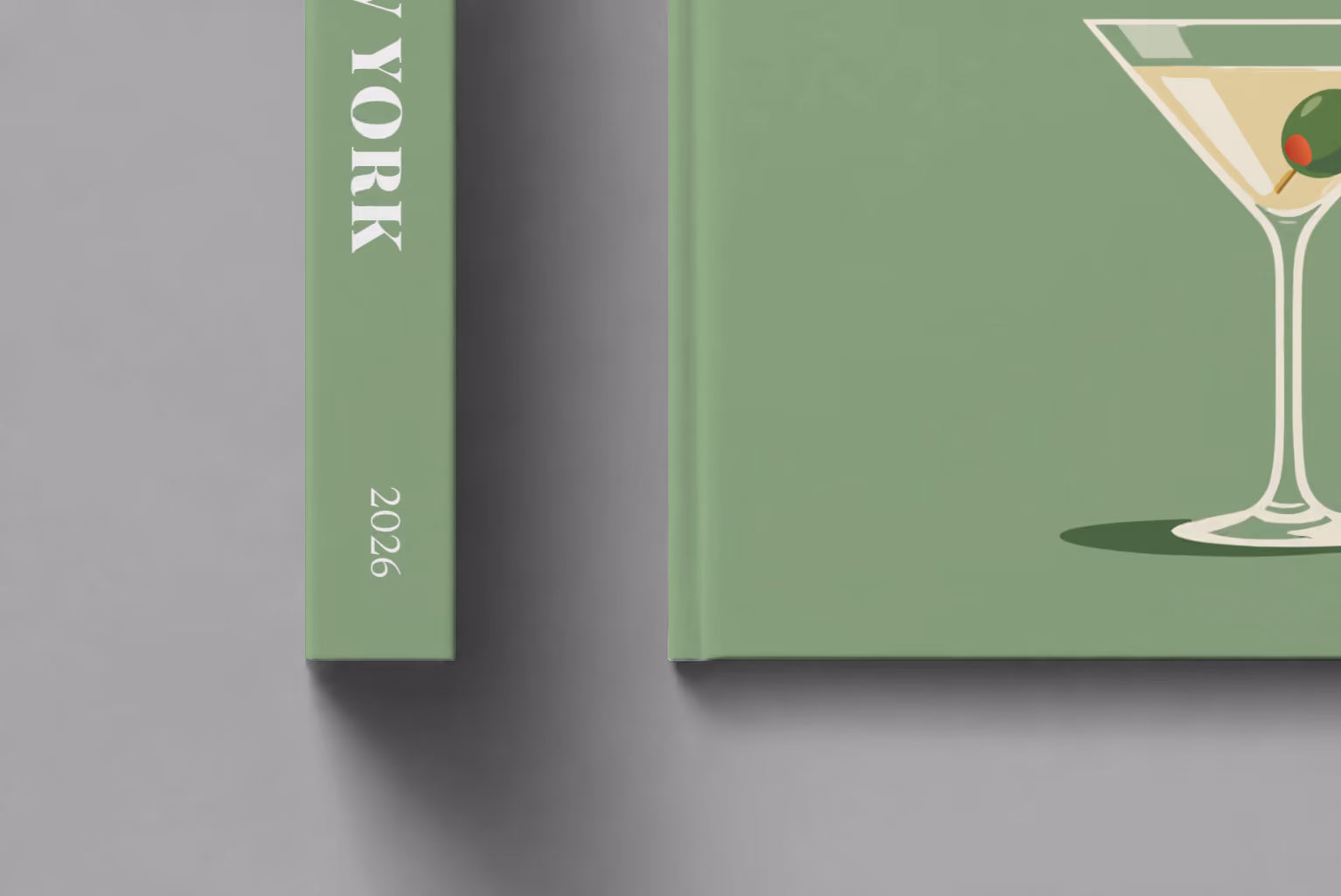 New York hardcover photo book with the illustrated cover of a martini with an olive on sage green, shown close up beside its spine on a pale grey studio surface