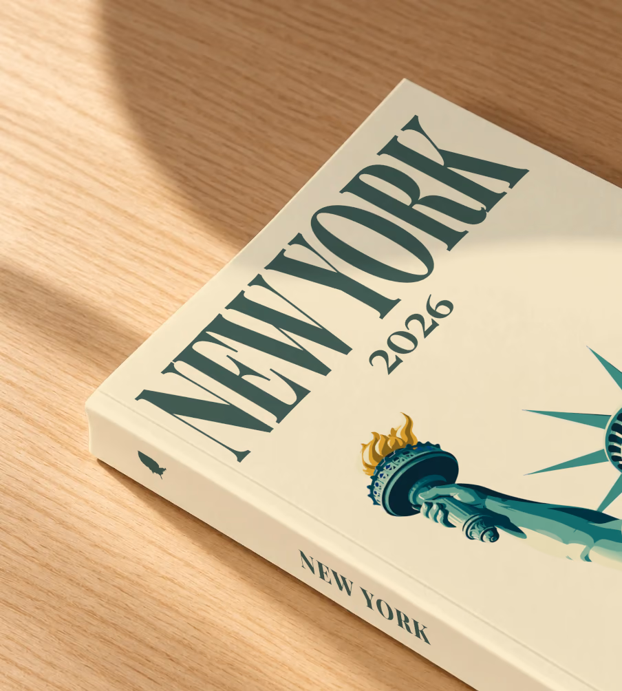 New York softcover photo book with the illustrated cover of the Statue of Liberty on cream, lying on an oak desk in dappled afternoon sunlight