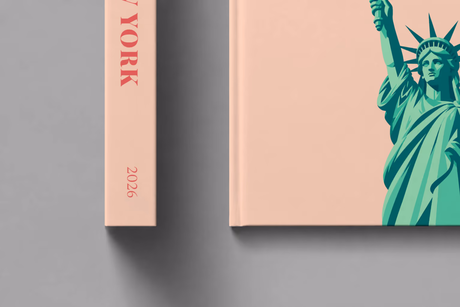 New York hardcover photo book with the illustrated cover of the Statue of Liberty on peach, shown close up beside its spine on a pale grey studio surface