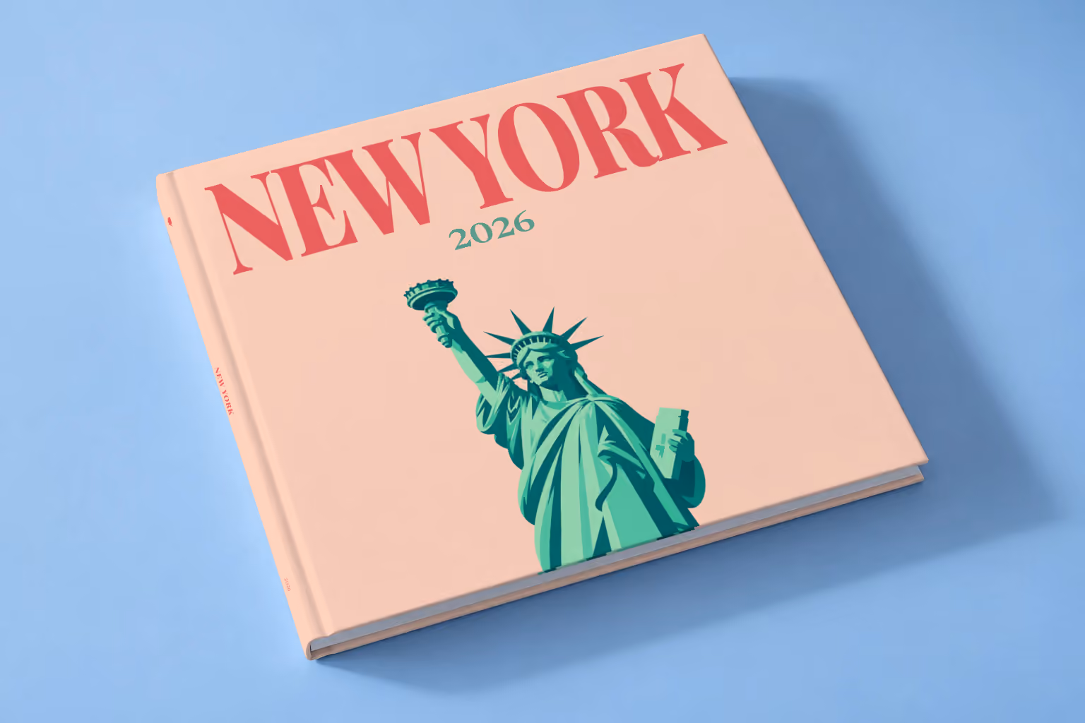 New York square hardcover photo book with the illustrated cover of the Statue of Liberty on peach, lying on a pale blue studio backdrop