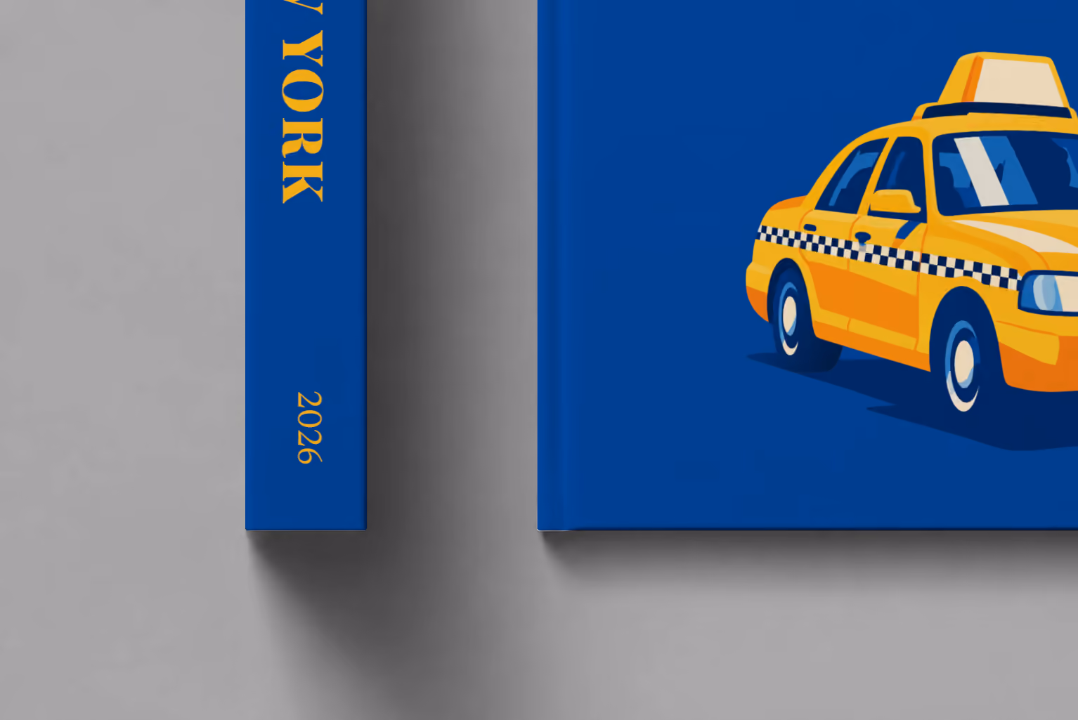 New York hardcover photo book with the illustrated cover of a yellow taxi on royal blue, shown close up beside its spine on a pale grey studio surface