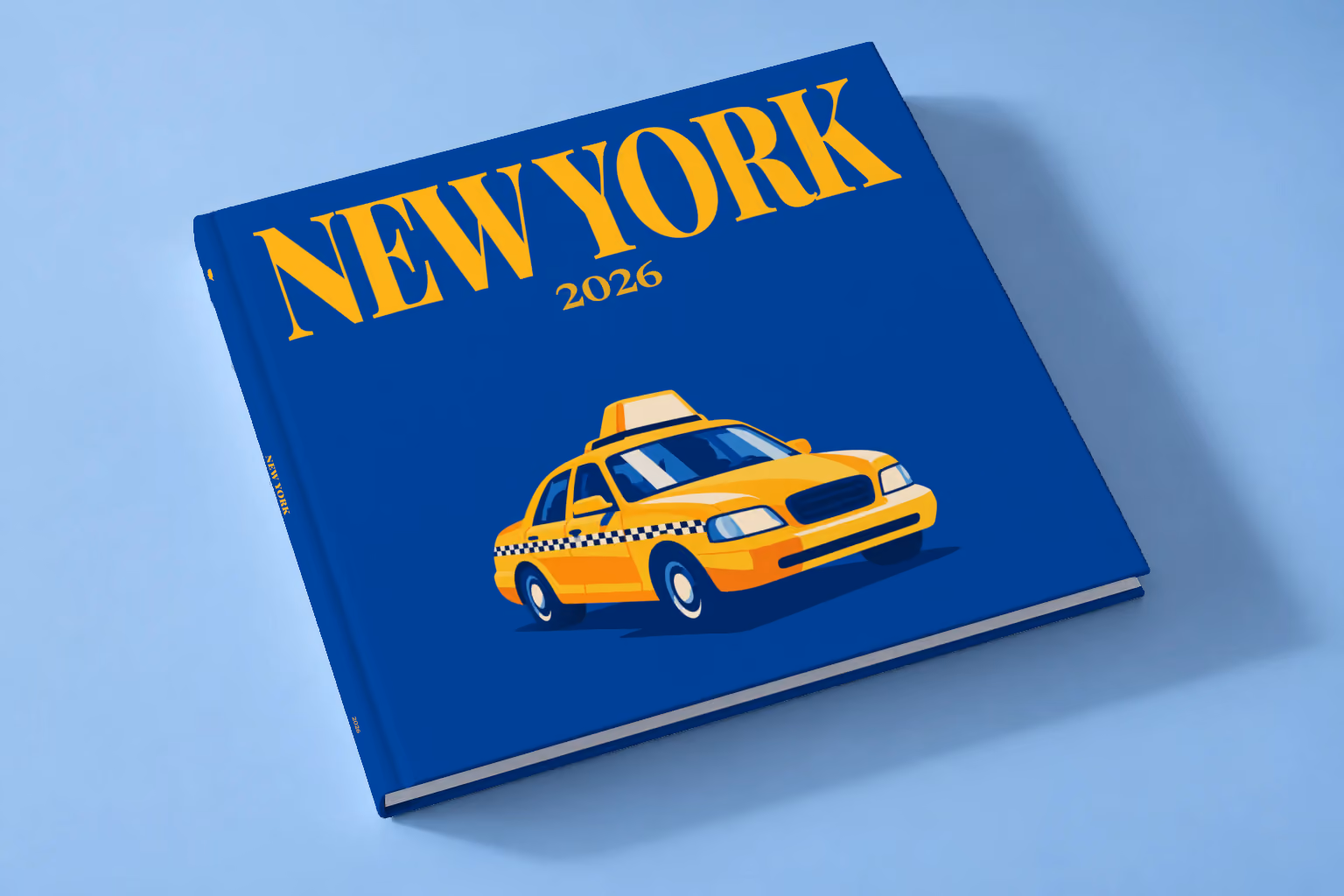 New York square hardcover photo book with the illustrated cover of a yellow taxi on royal blue, lying on a pale blue studio backdrop