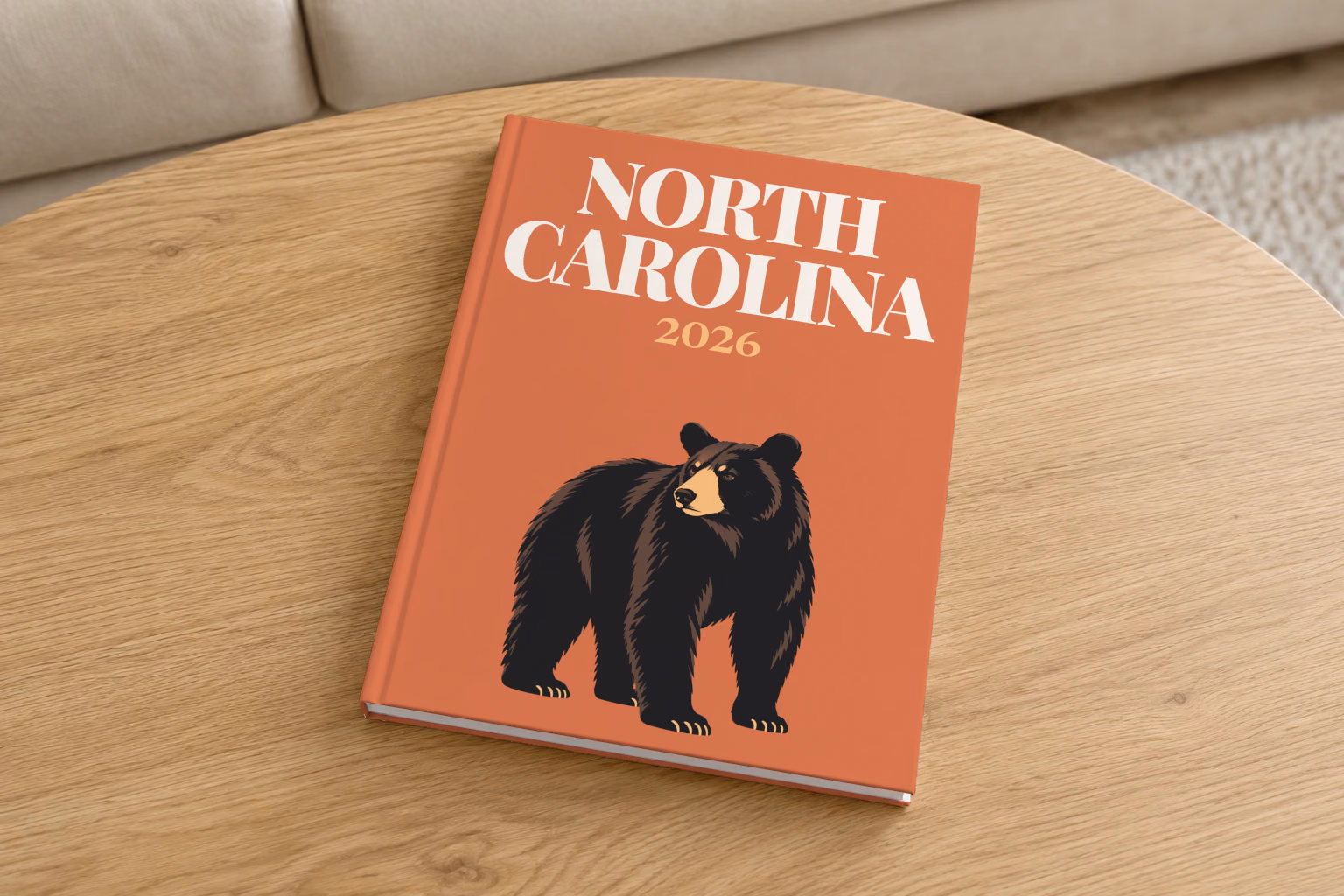 North Carolina hardcover photo book with the illustrated cover of a black bear on burnt orange, on a round oak coffee table in a bright living room