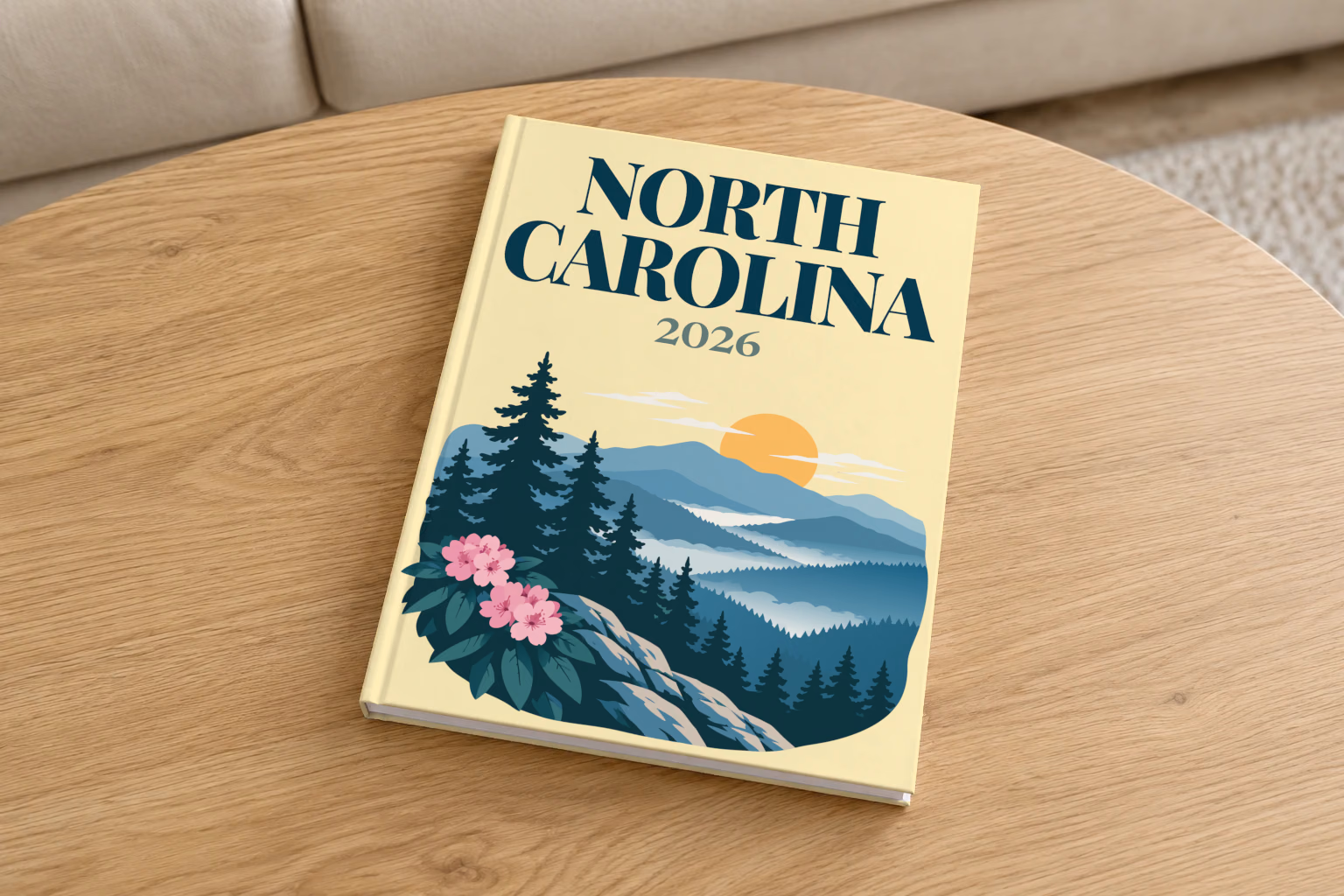North Carolina hardcover photo book with the illustrated cover of the Blue Ridge Mountains with pine trees and pink rhododendron on pale yellow, on a round oak coffee table in a bright living room