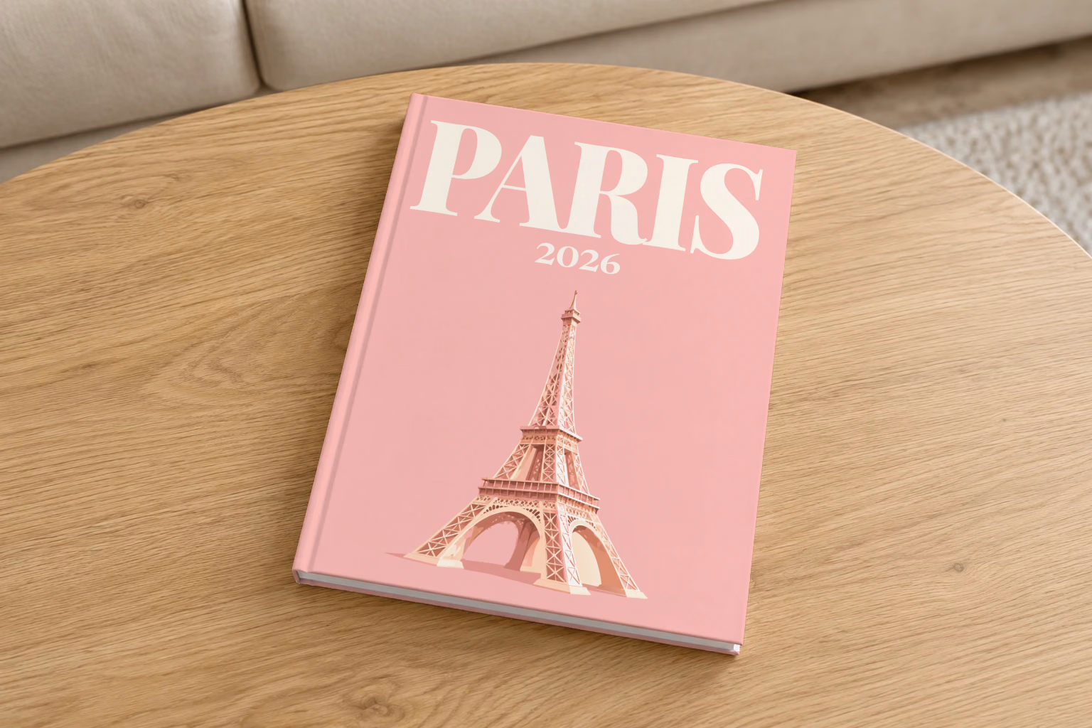 Paris hardcover photo book with the illustrated cover of the Eiffel Tower on blush pink, on a round oak coffee table in a bright living room