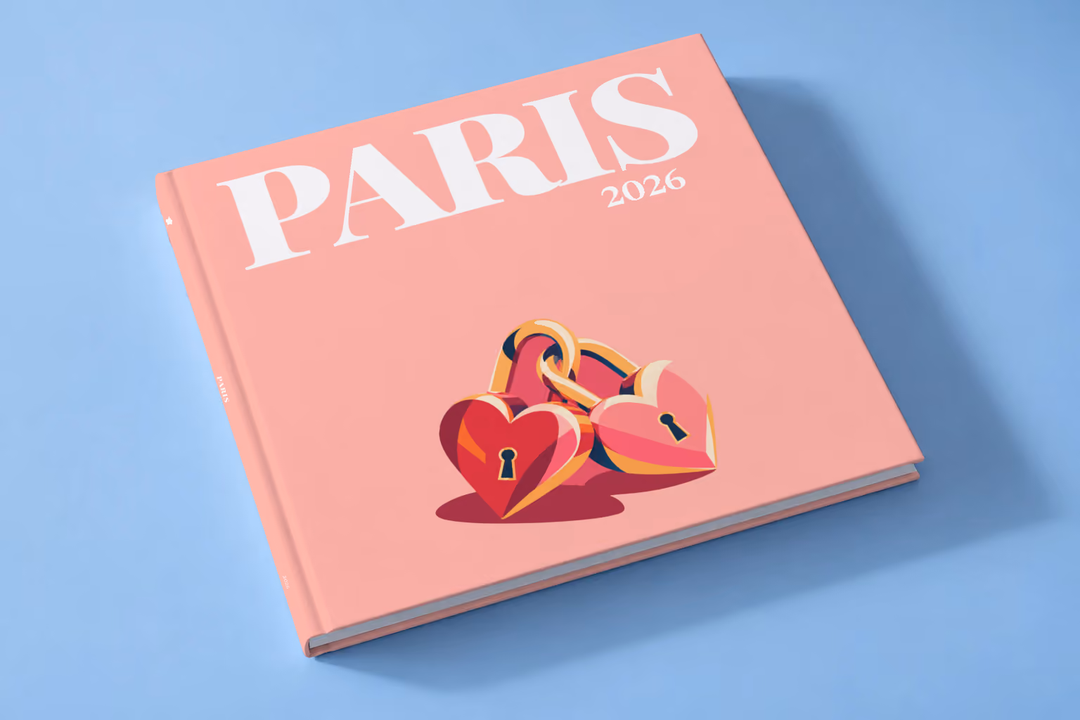 Paris square hardcover photo book with the illustrated cover of heart-shaped love locks on salmon pink, lying on a pale blue studio backdrop