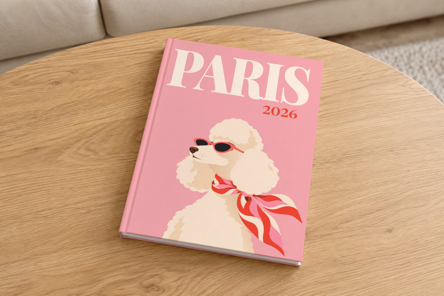 Paris hardcover photo book with the illustrated cover of a poodle in sunglasses and a scarf on pink, on a round oak coffee table in a bright living room