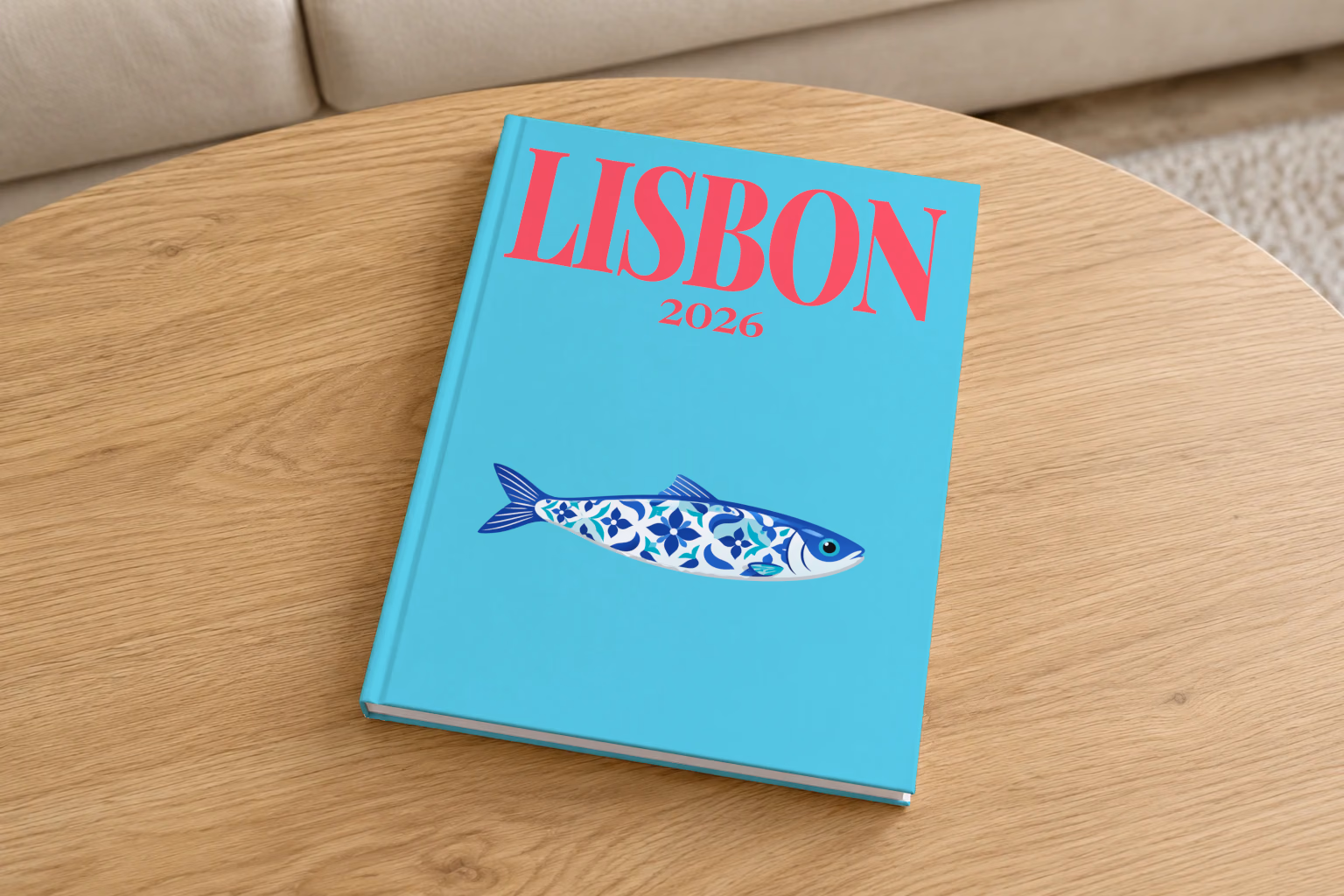 Portugal hardcover photo book with the Lisbon illustrated cover of a blue azulejo-tiled Portuguese sardine on turquoise, on a round oak coffee table in a bright living room