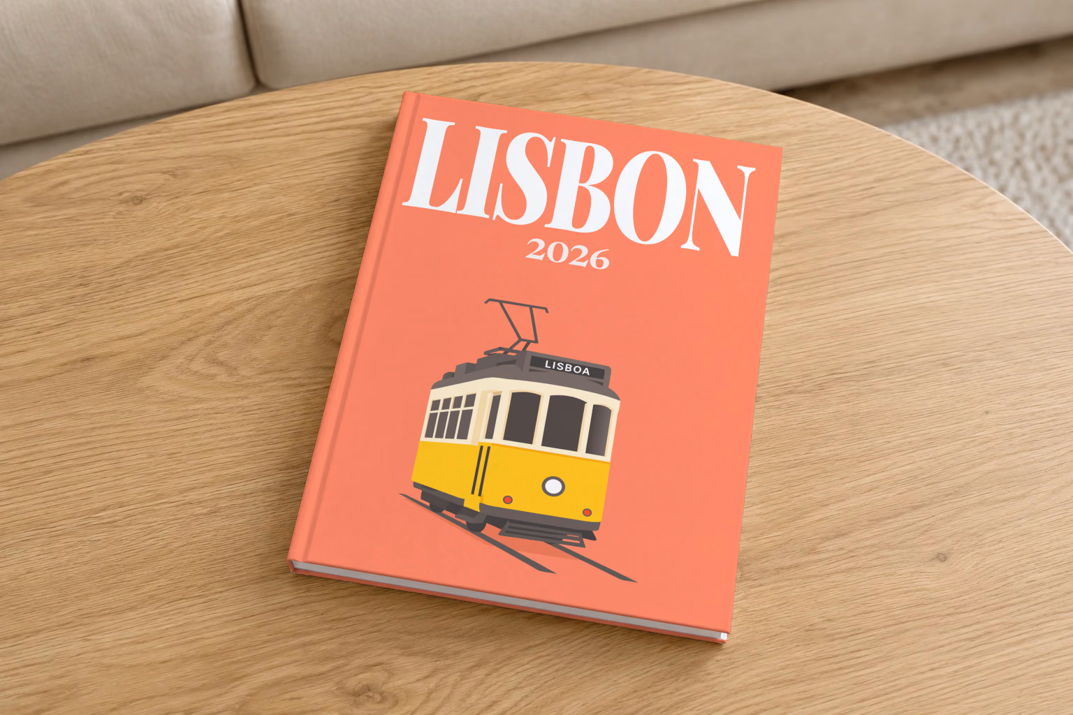 Portugal hardcover photo book with the Lisbon illustrated cover of a yellow vintage Lisbon Tram 28 on coral, on a round oak coffee table in a bright living room