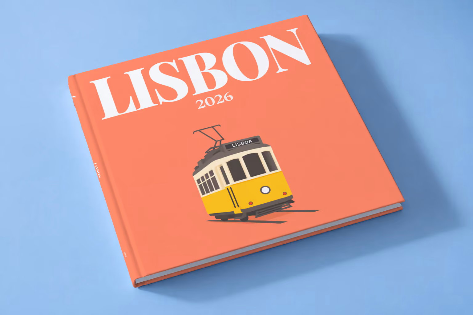 Portugal square hardcover photo book with the Lisbon illustrated cover of a yellow vintage Lisbon Tram 28 on coral, lying on a pale blue studio backdrop