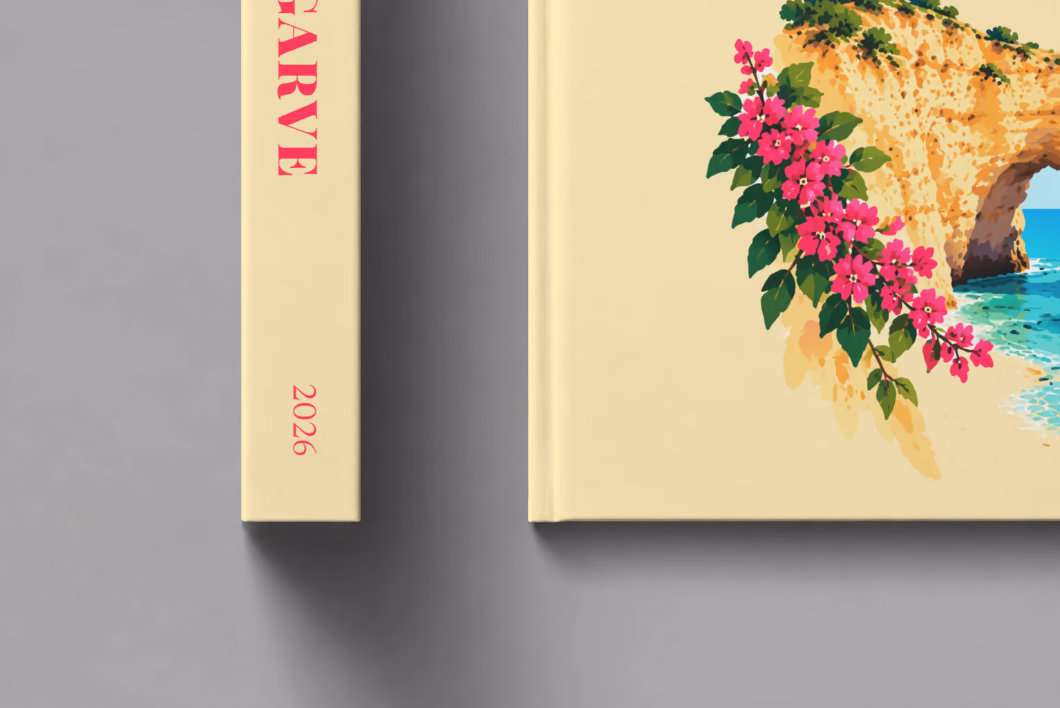 Portugal hardcover photo book with the Algarve illustrated cover of a golden Algarve sea arch over turquoise water with pink bougainvillea on pale yellow, shown close up beside its spine on a pale grey studio surface