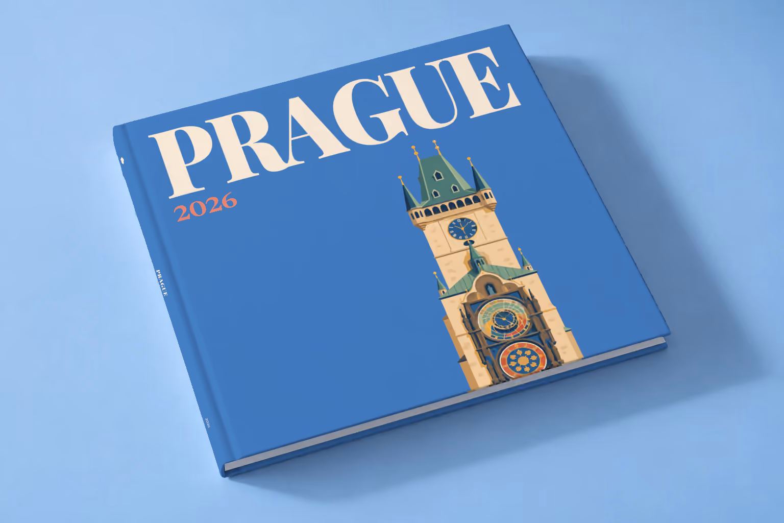 Prague square hardcover photo book with the illustrated cover of the Prague Astronomical Clock tower on blue, lying on a pale blue studio backdrop