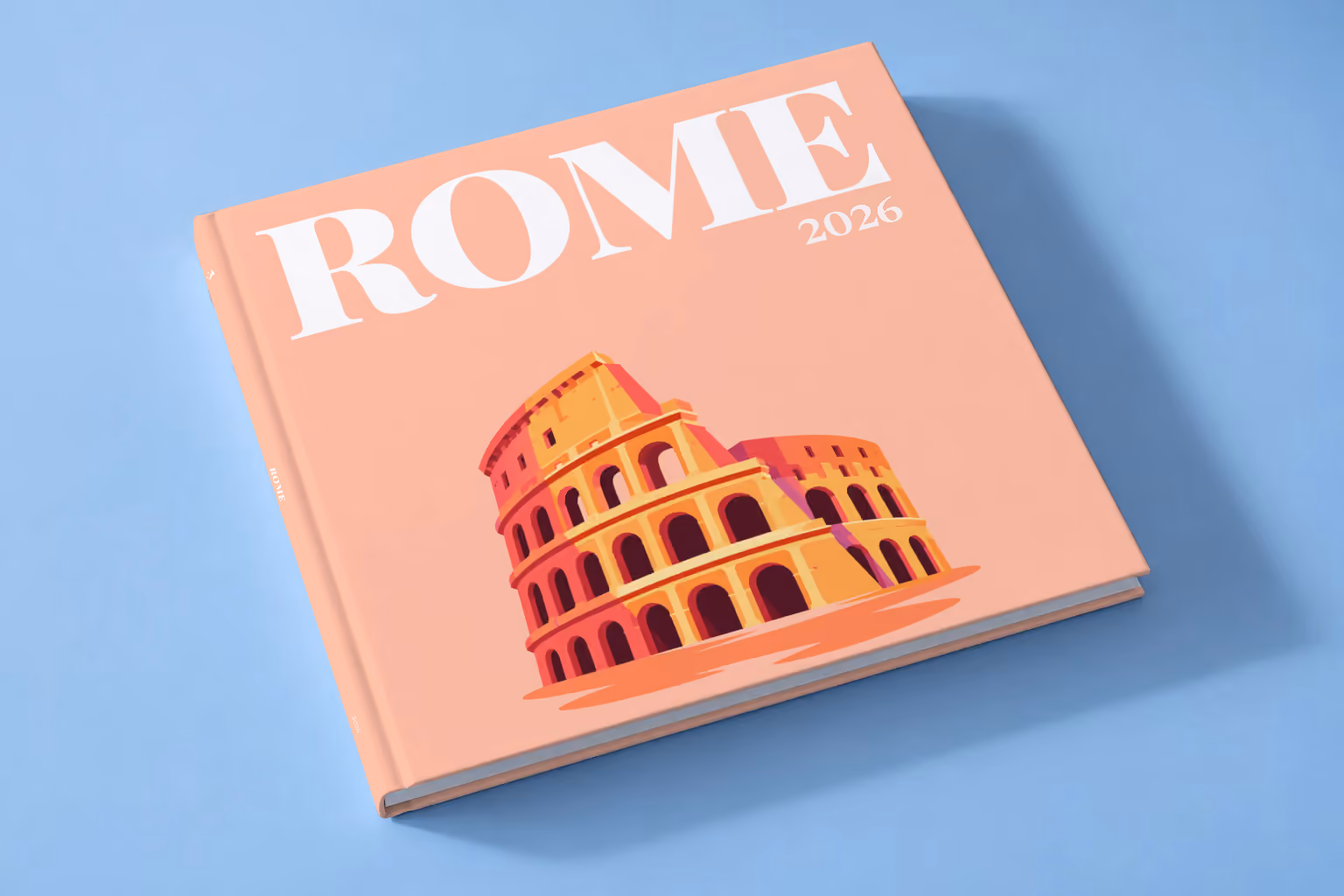 Rome square hardcover photo book with the illustrated cover of the Colosseum on peach, lying on a pale blue studio backdrop