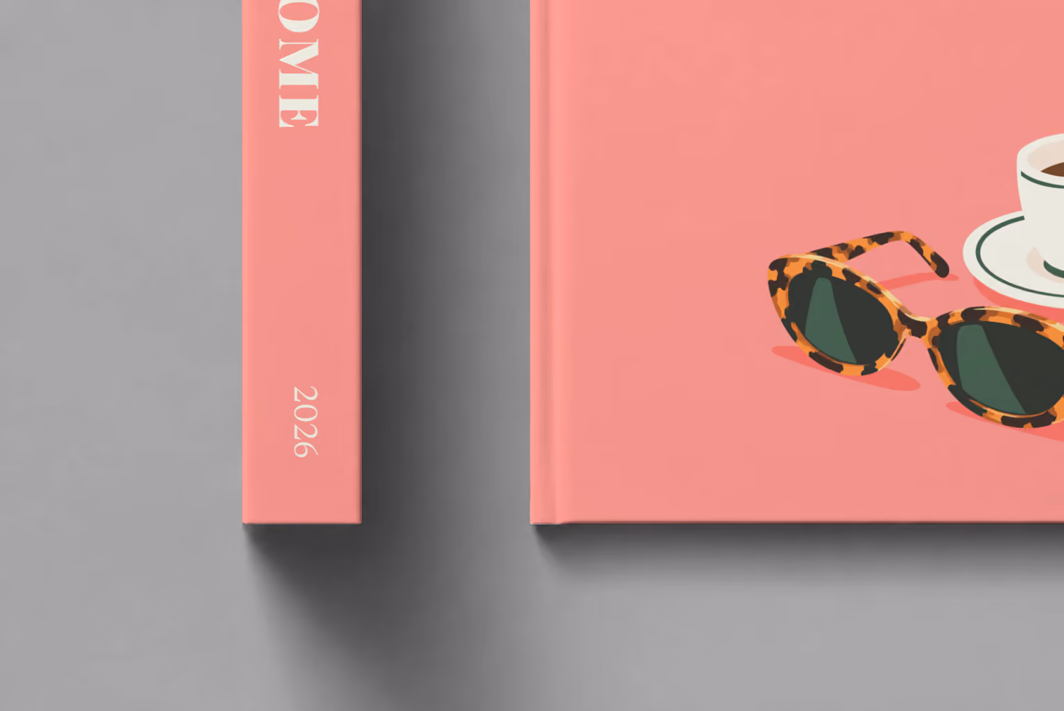 Rome hardcover photo book with the illustrated cover of an espresso cup and tortoiseshell sunglasses on salmon pink, shown close up beside its spine on a pale grey studio surface