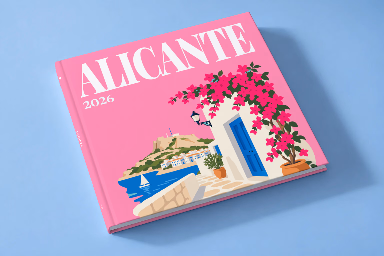 Spain square hardcover photo book with the Alicante illustrated cover of a whitewashed street with bougainvillea above the sea on pink, lying on a pale blue studio backdrop