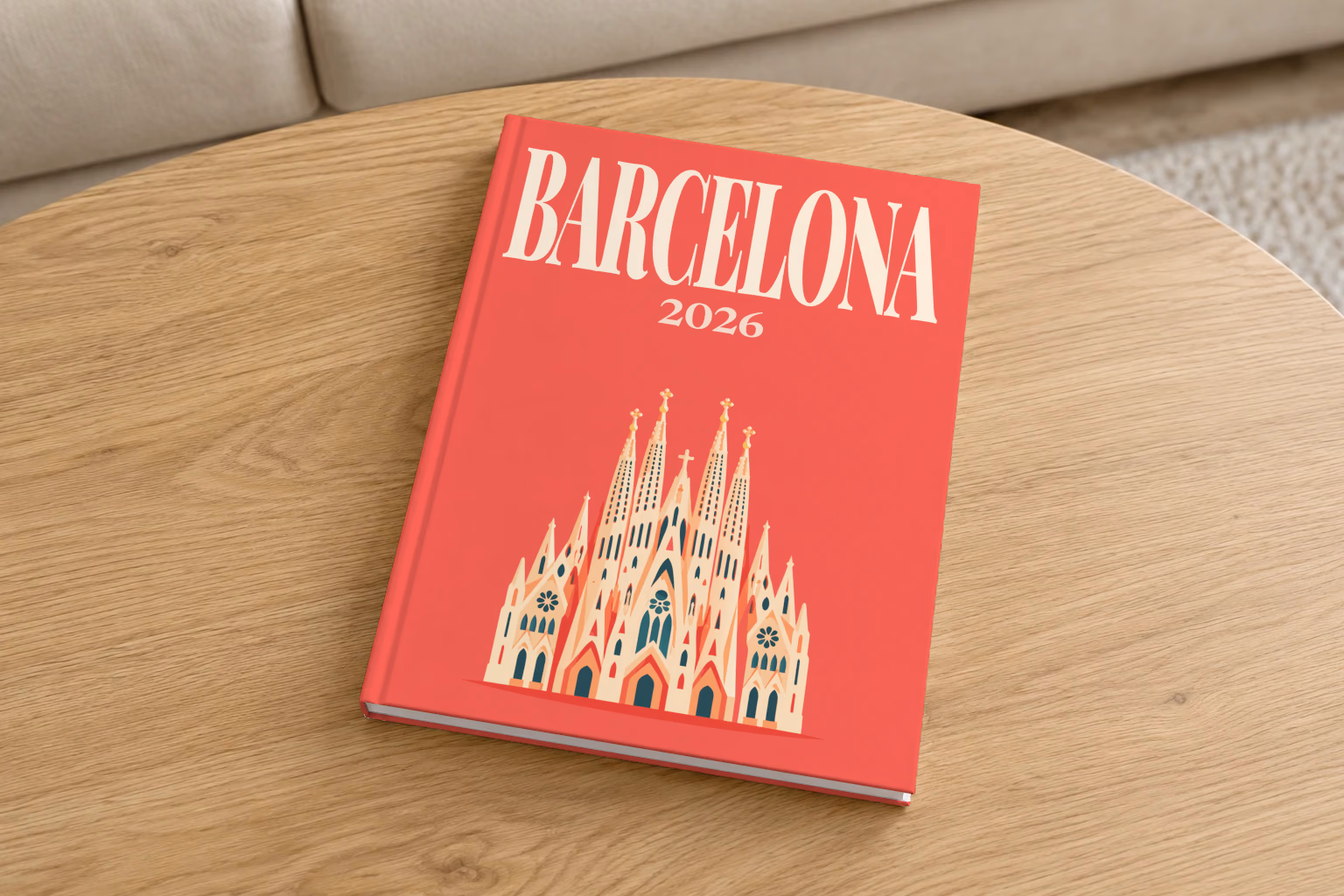 Spain hardcover photo book with the Barcelona illustrated cover of the Sagrada Família on coral red, on a round oak coffee table in a bright living room