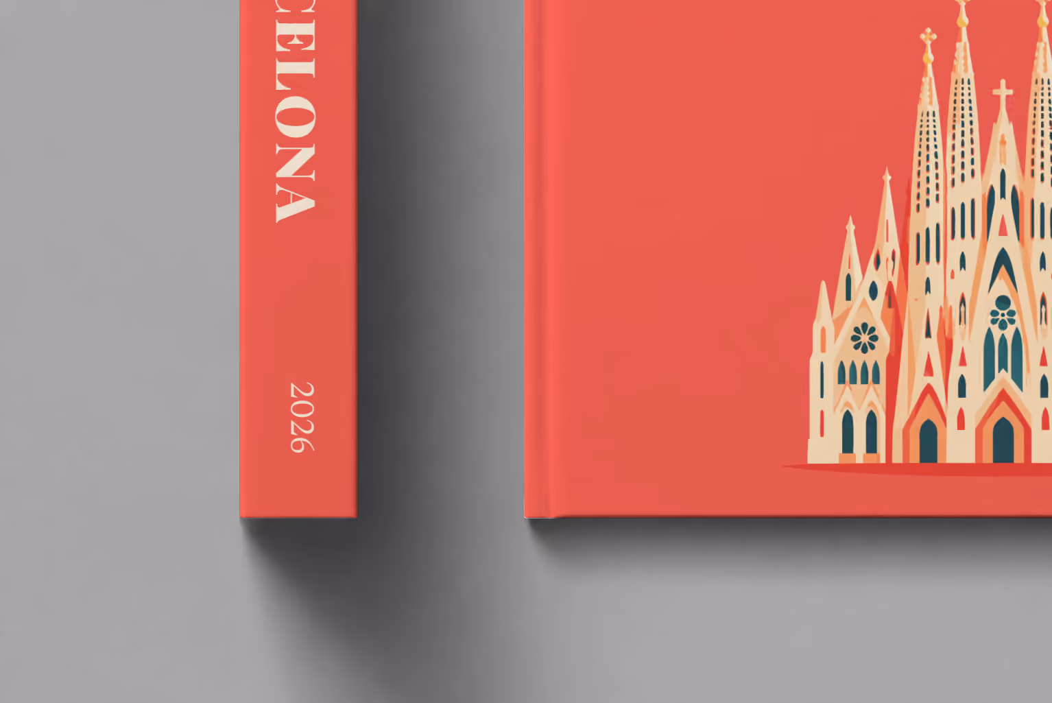 Spain hardcover photo book with the Barcelona illustrated cover of the Sagrada Família on coral red, shown close up beside its spine on a pale grey studio surface