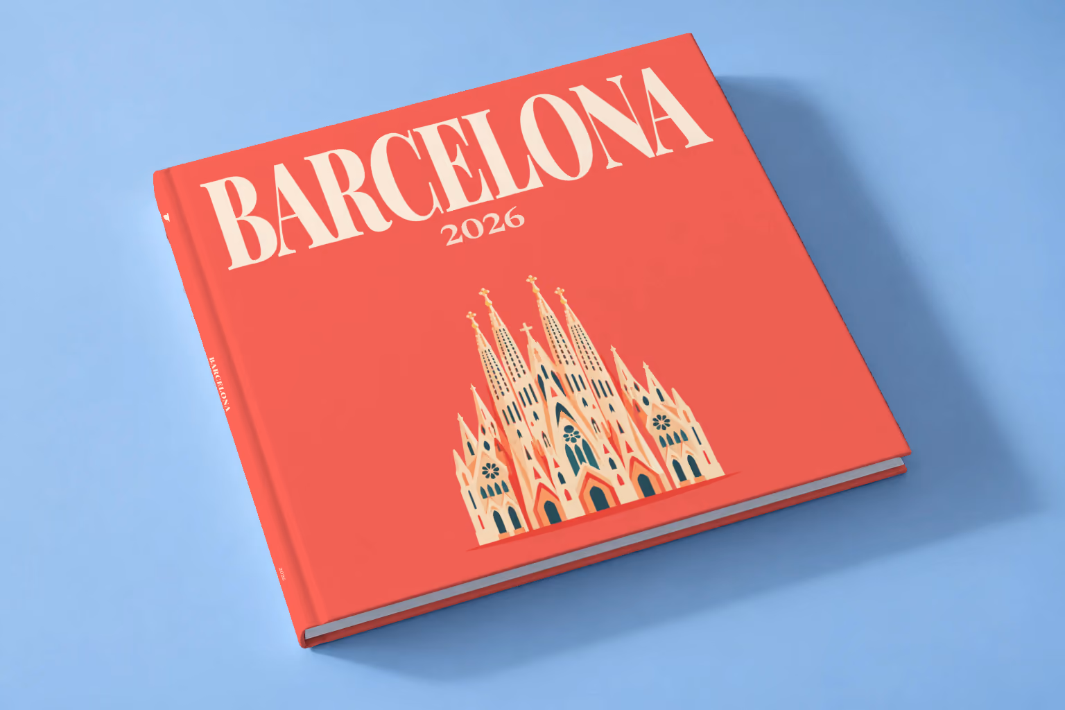 Spain square hardcover photo book with the Barcelona illustrated cover of the Sagrada Família on coral red, lying on a pale blue studio backdrop