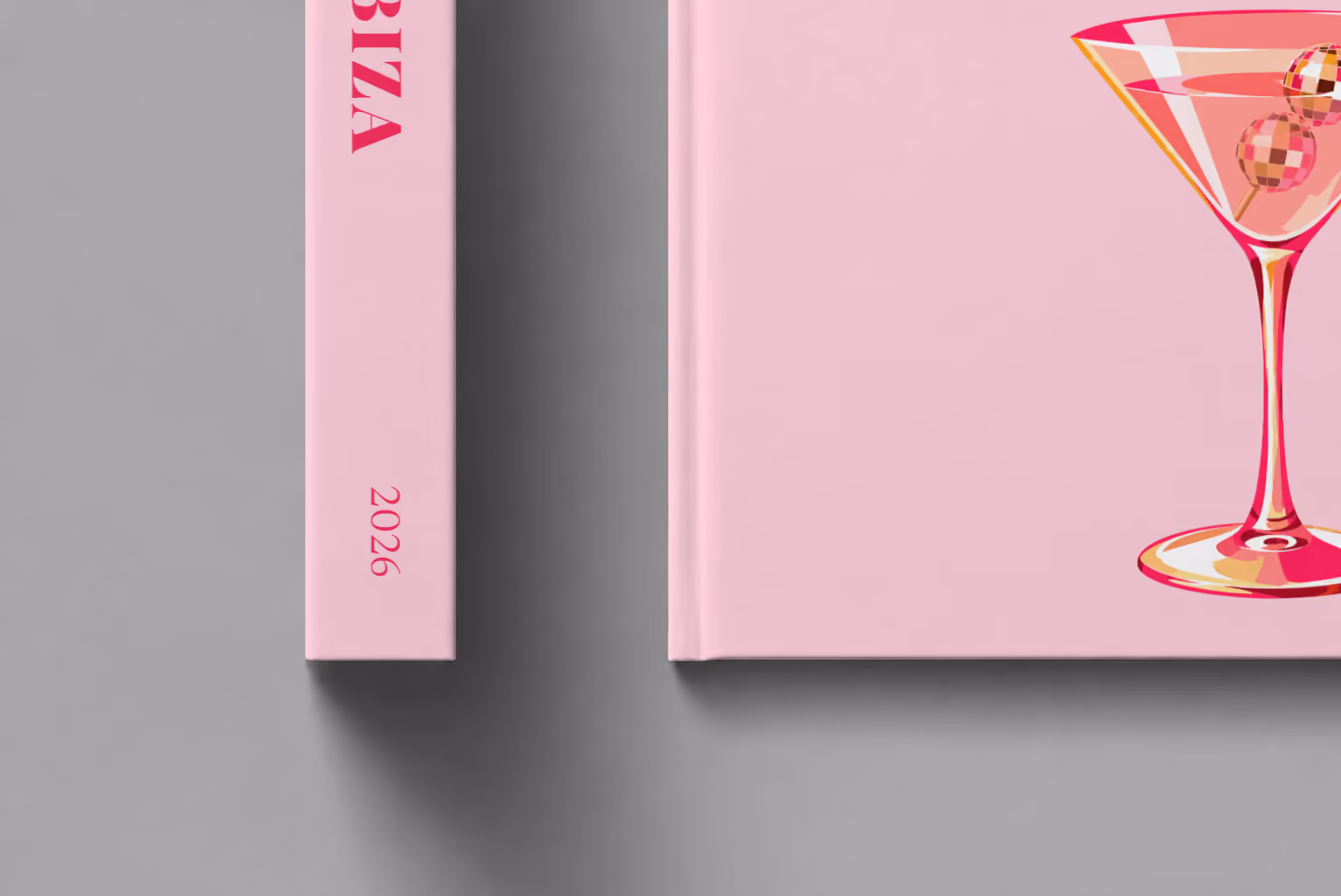 Spain hardcover photo book with the Ibiza illustrated cover of a martini with a disco-ball garnish on pale pink, shown close up beside its spine on a pale grey studio surface