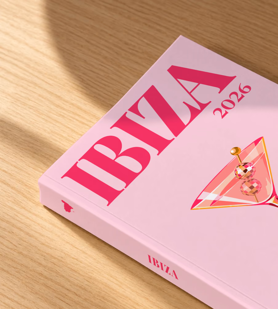 Spain softcover photo book with the Ibiza illustrated cover of a martini with a disco-ball garnish on pale pink, lying on an oak desk in dappled afternoon sunlight