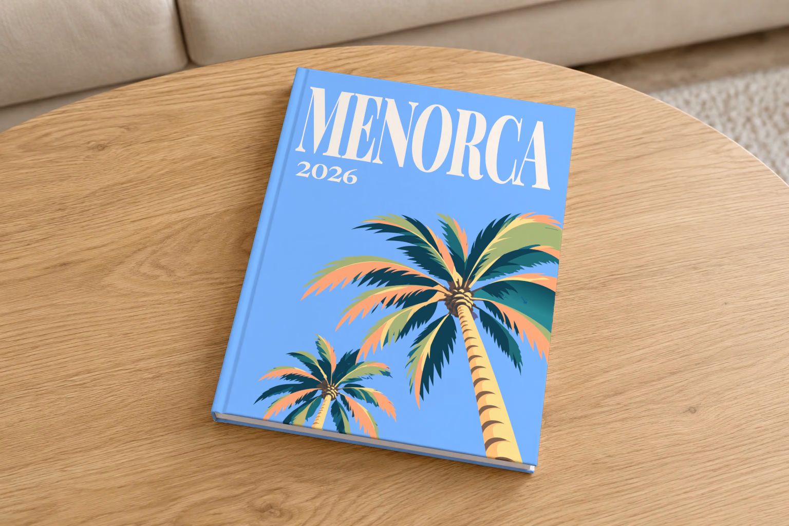 Spain hardcover photo book with the Menorca illustrated cover of palm trees on blue, on a round oak coffee table in a bright living room