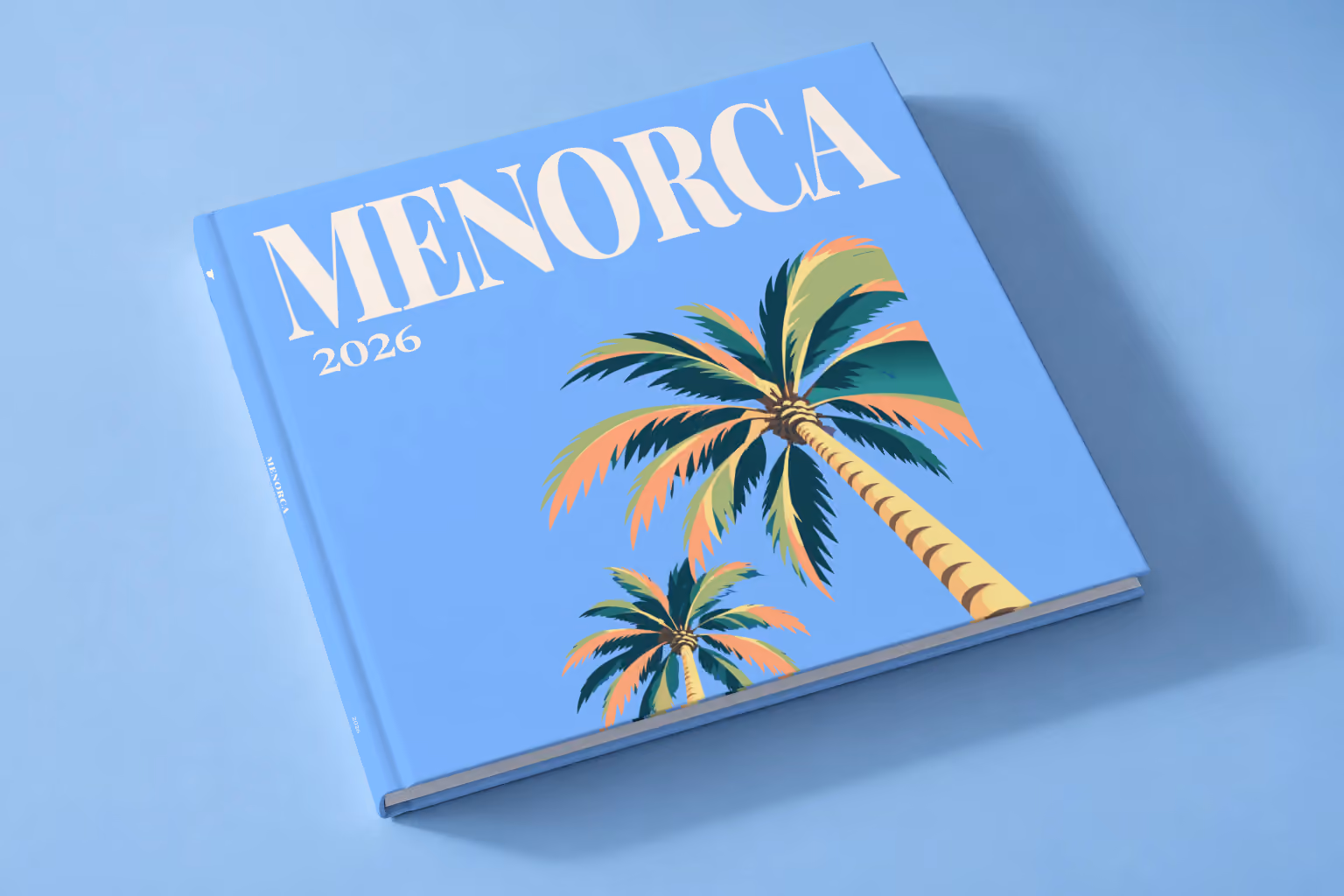 Spain square hardcover photo book with the Menorca illustrated cover of palm trees on blue, lying on a pale blue studio backdrop