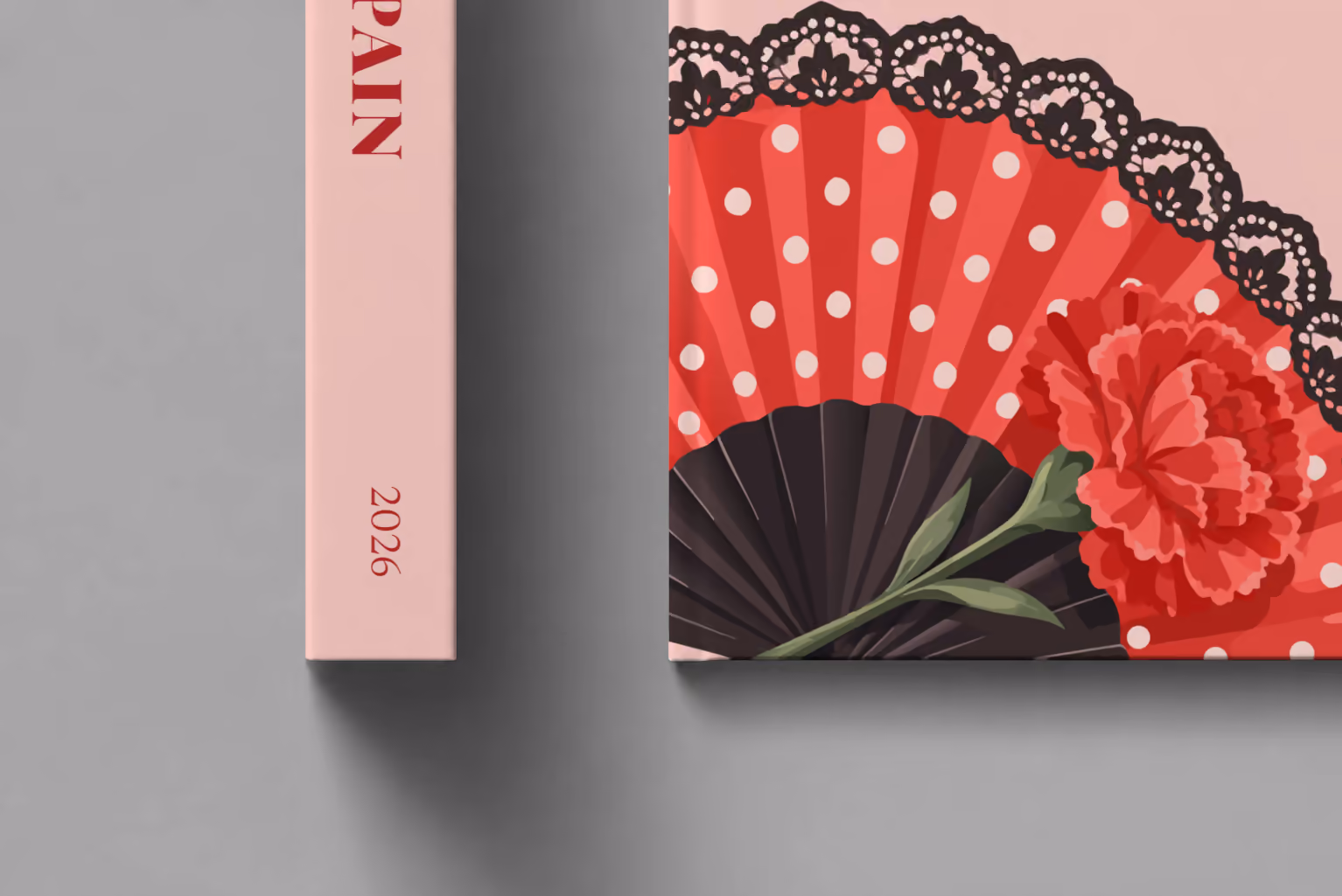 Spain hardcover photo book with the illustrated cover of a polka-dot flamenco fan and a carnation on blush pink, shown close up beside its spine on a pale grey studio surface