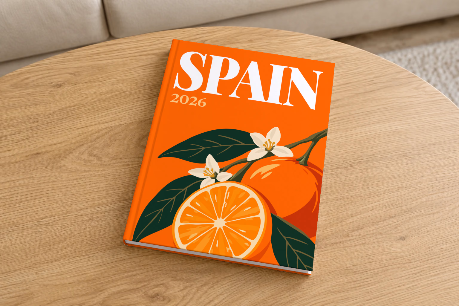 Spain hardcover photo book with the illustrated cover of a halved orange and orange blossom on orange, on a round oak coffee table in a bright living room