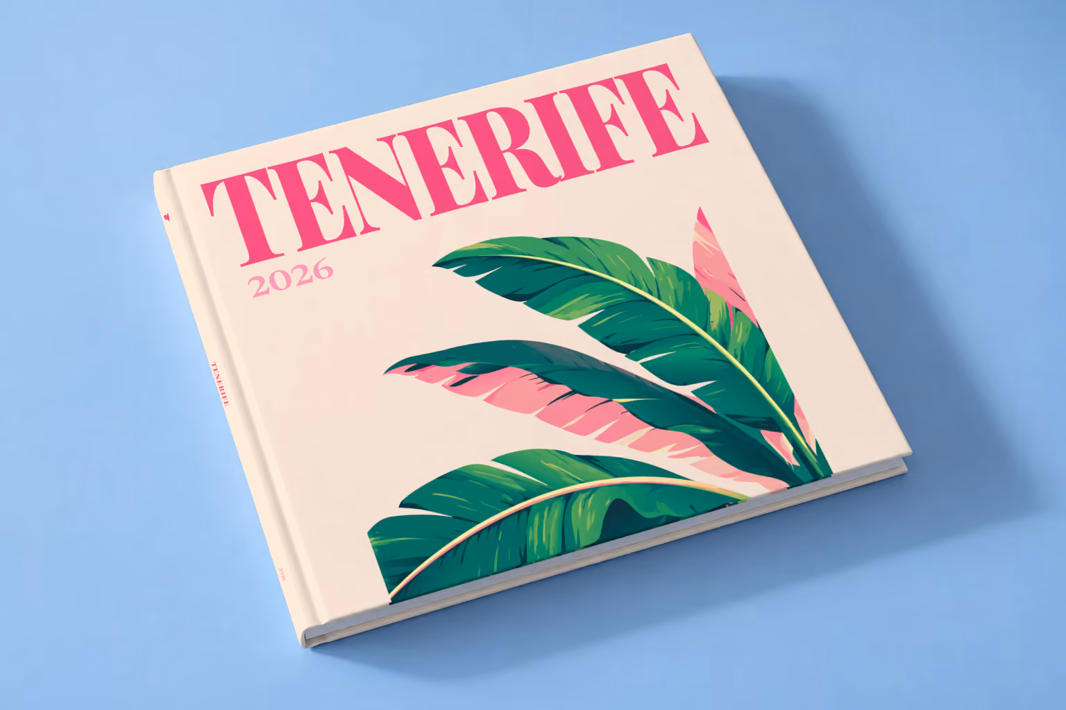 Spain square hardcover photo book with the Tenerife illustrated cover of banana leaves on cream, lying on a pale blue studio backdrop