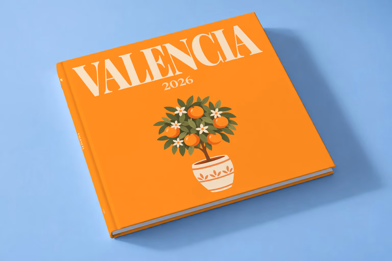 Spain square hardcover photo book with the Valencia illustrated cover of a potted orange tree on orange, lying on a pale blue studio backdrop