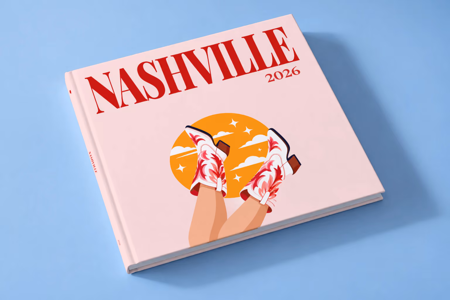 Tennessee square hardcover photo book with the Nashville illustrated cover of kicking legs in red and white cowboy boots against a yellow sun on pale pink, lying on a pale blue studio backdrop