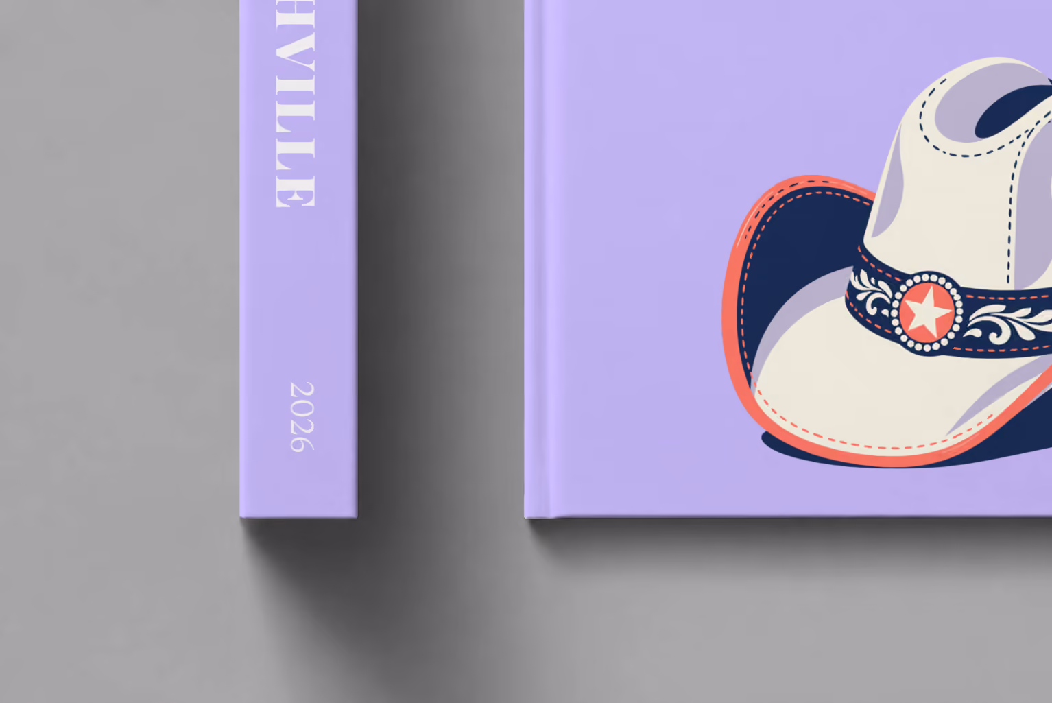 Tennessee hardcover photo book with the Nashville illustrated cover of a white cowboy hat with music notes on lavender, shown close up beside its spine on a pale grey studio surface