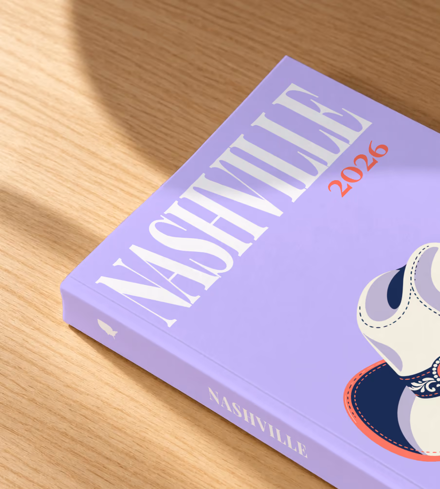 Tennessee softcover photo book with the Nashville illustrated cover of a white cowboy hat with music notes on lavender, lying on an oak desk in dappled afternoon sunlight